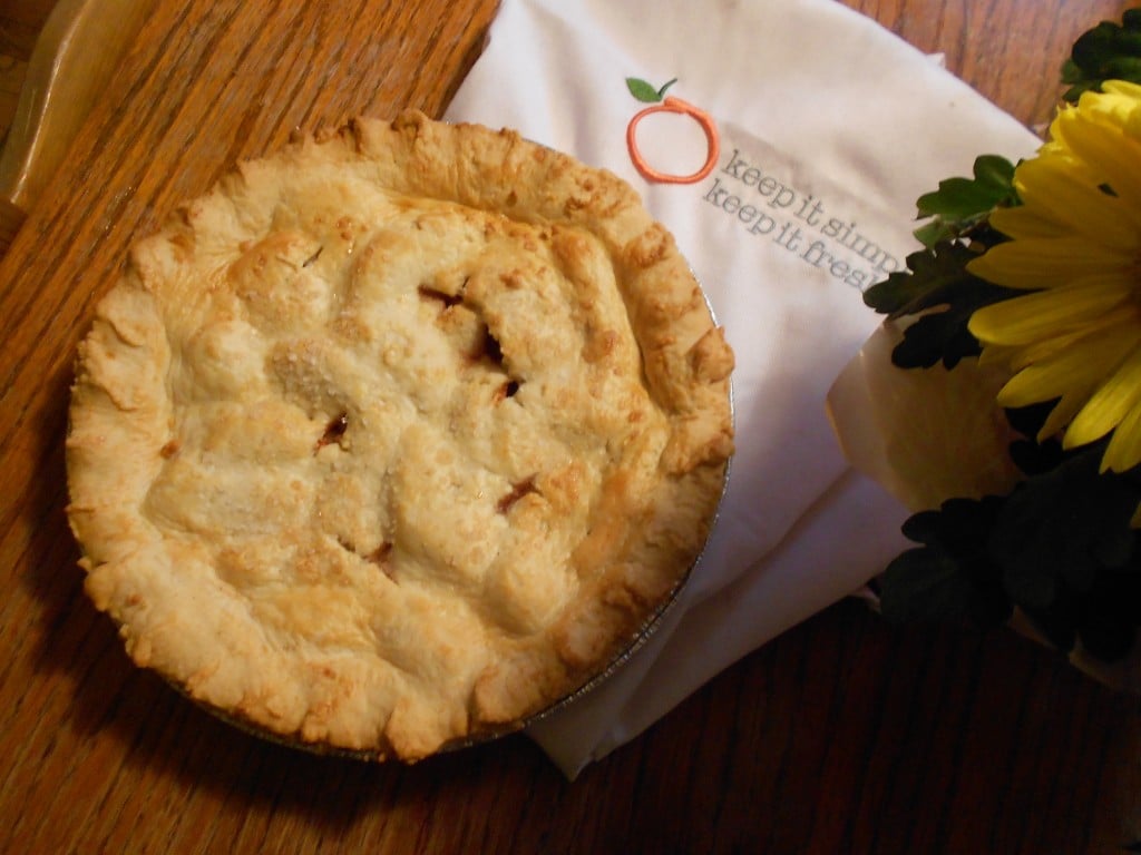 A fresh apple pie without cinnamon sitting on a counter with an apron underneath it.