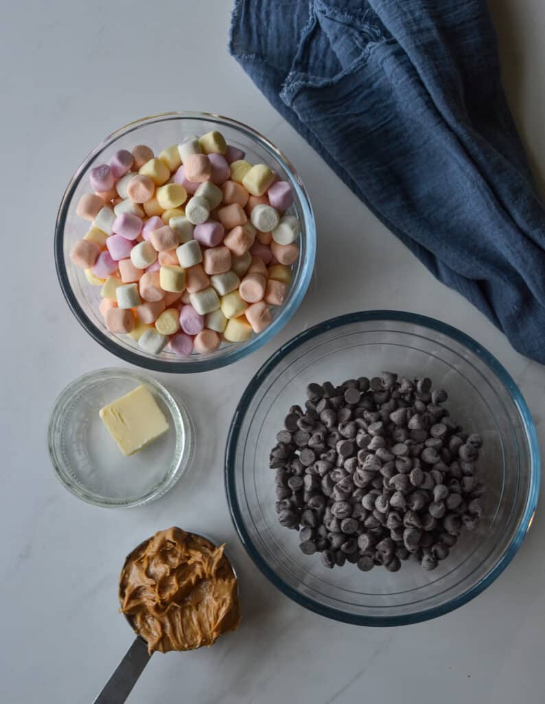 Overhead view of mini marshmallows, chocolate chips, peanut butter and butter.