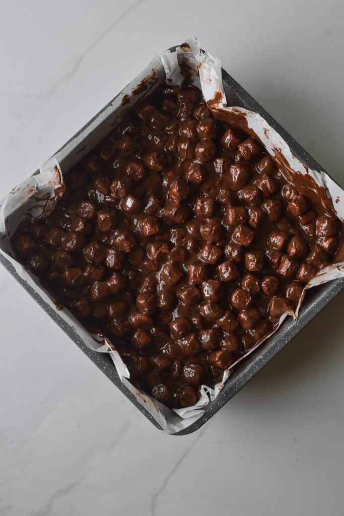 Chocolate Peanut Butter Marshmallow squares in an 8 inch pan lined with parchment paper.