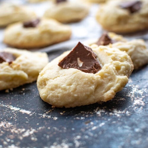 Shortbread Toblerone cookies featuring a large chunk of Toblerone chocolate bar in the centre of a shortbread cookie on a well worn baking sheet.
