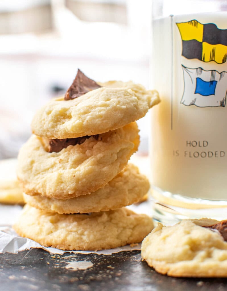 A stack of Toblerone shortbread cookies reseting against a glass of milk.