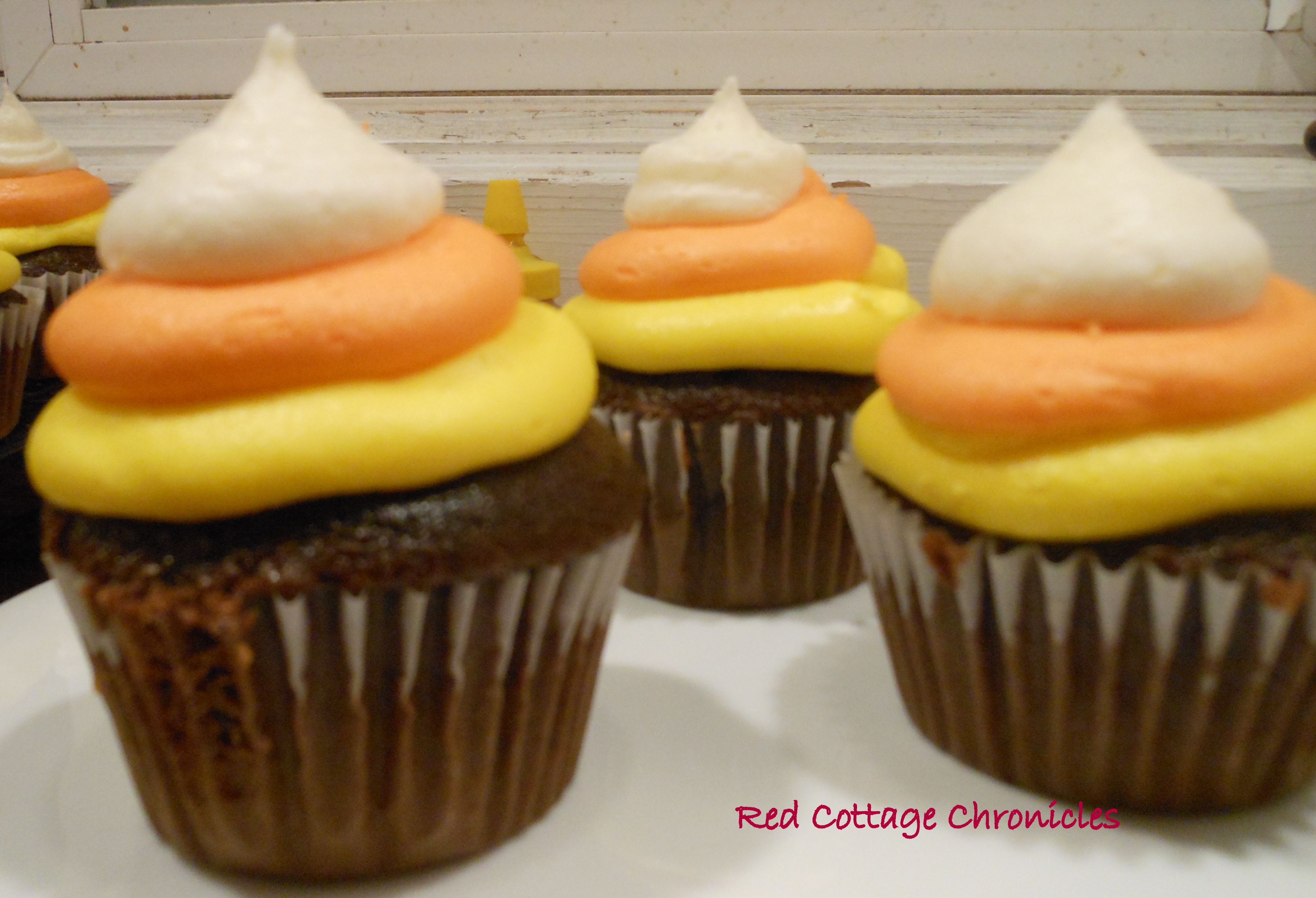 Chocolate cupcakes with rings of yellow, orange and white frosting to look like candy corn.