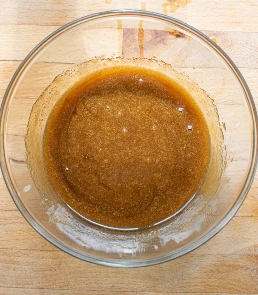 Corn syrup, melted butter and brown sugar in a glass mixing bowl before whisking.