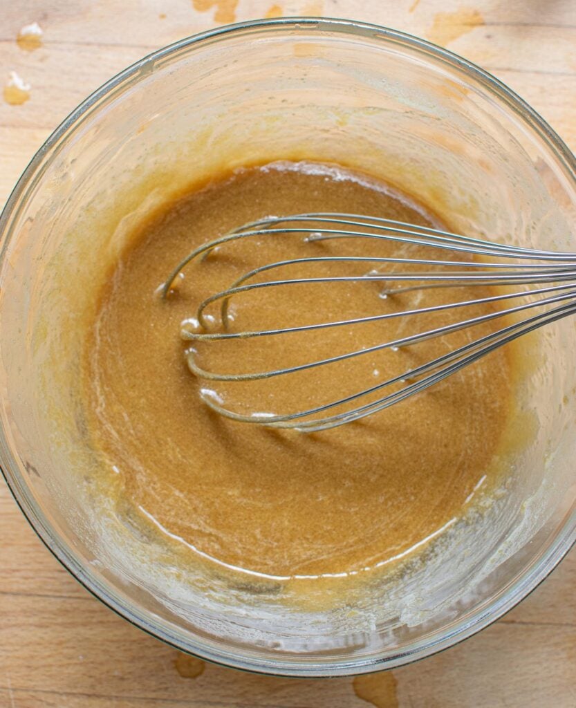 Melted butter, corn syrup and brown sugar whisked together in a glass mixing bowl.