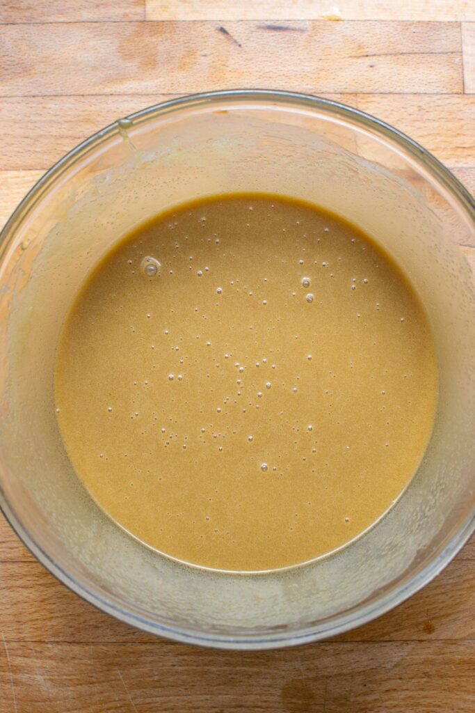 Butter tart filling all whisked together in a glass mixing bowl.
