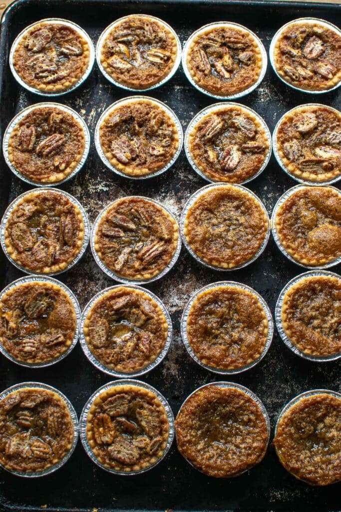 Freshly baked pecan butter tarts on a sheet pan.