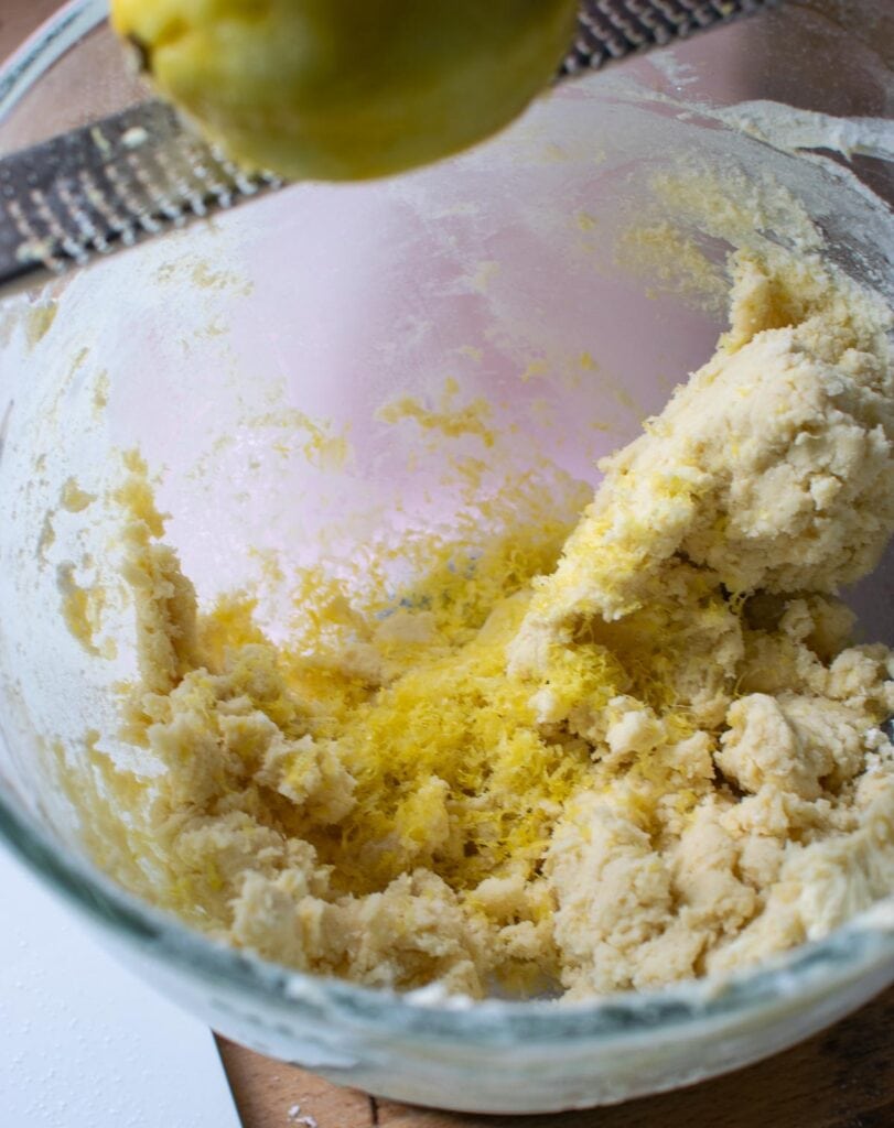 Fresh lemon zest being grated into shortbread dough.