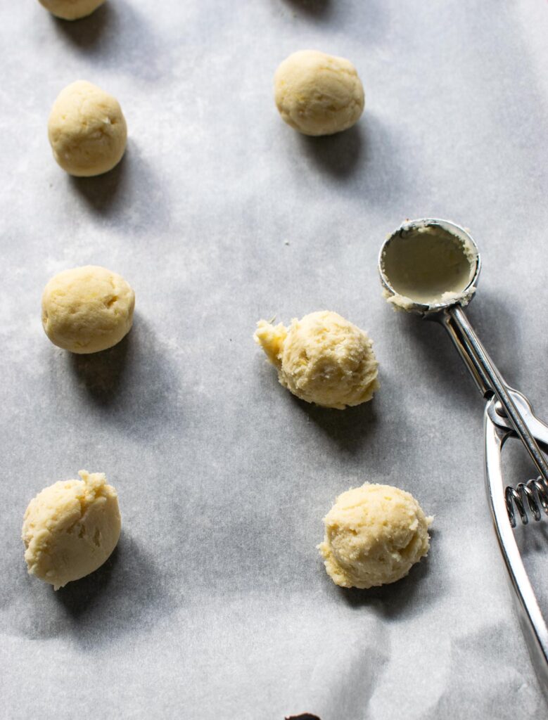 lemon shortbread cookie dough scooped out onto a cookie sheet into ball shapes before baking.