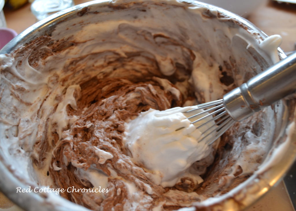 Fold egg whites into chocolate batter starting with 1/4 egg whites first and then adding remainder, folding gently just until no egg white streaks remain