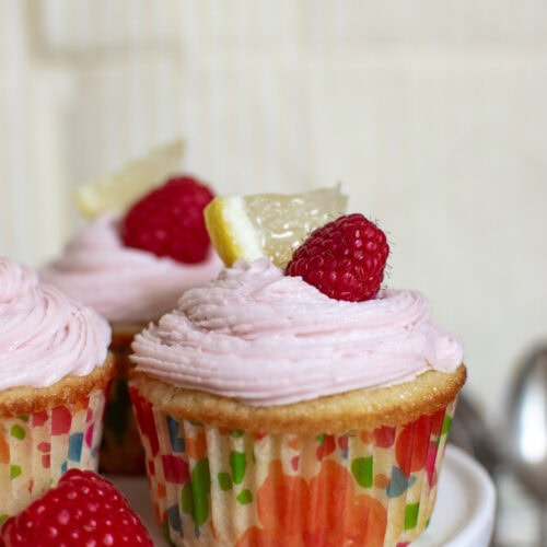 Pink Lemonade Cupcakes garnished with a lemon slice and fresh raspberry.