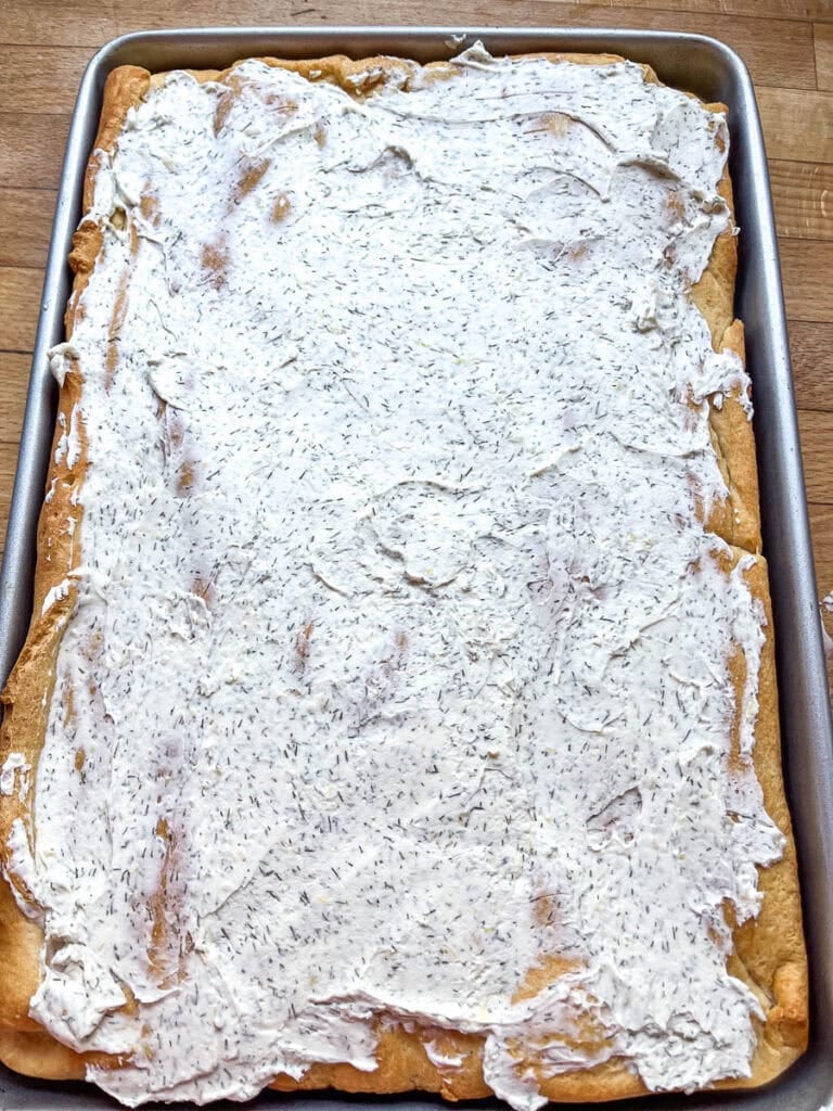 Crescent rolls that have been rolled and baked on a rimmed cookie sheet, and topped with a lemon dill cream cheese mixture.