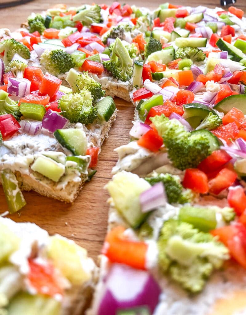 Veggie pizza squares topped with broccoli, red onion, green bell pepper and cucumbers.
