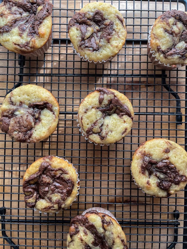 Freshly baked Nutella banana muffins on a black cooling rack.