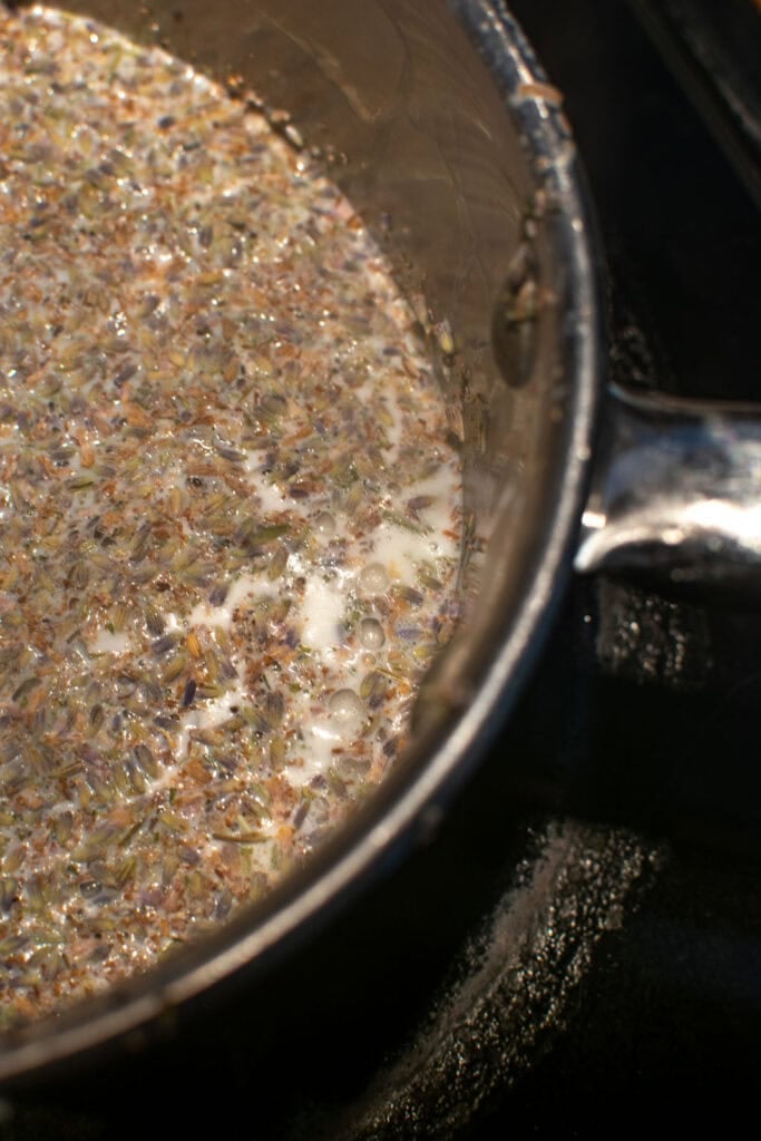 Culinary lavender buds added milk in a saucepan on the stove.