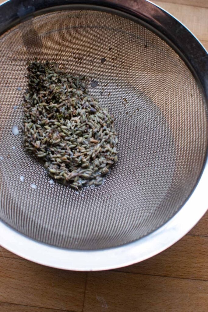 Lavender buds in a strainer after straining out of the milk in which they infused over low heat on the stove top.