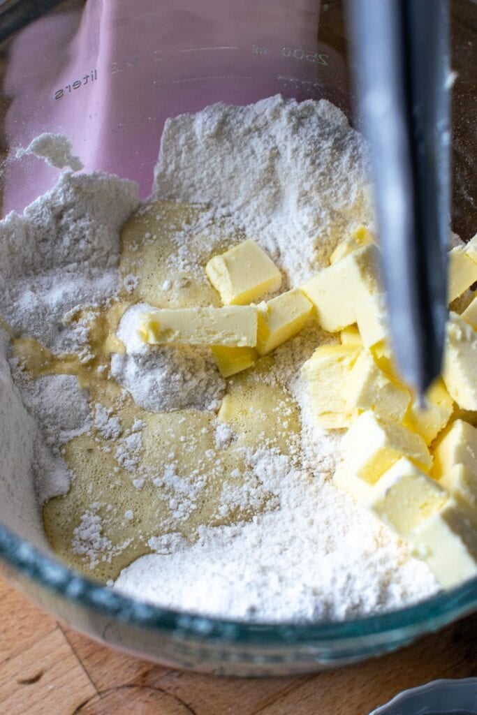 Cubes of butter added to the mixing bowl with dry ingredients, along with some of the milk and egg mixture, before being mixed in a stand mixer.