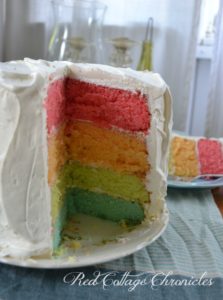 A 4 layer cake with pink, orange, green and blue layers.