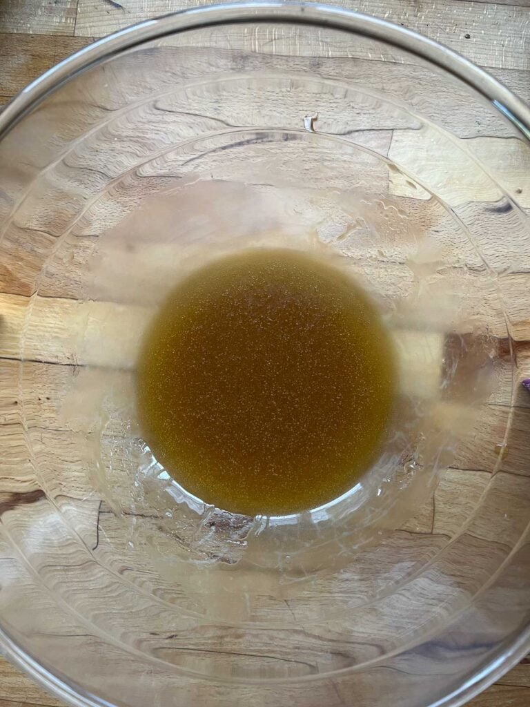Maple syrup and olive oil whisked together in a mixing bowl.