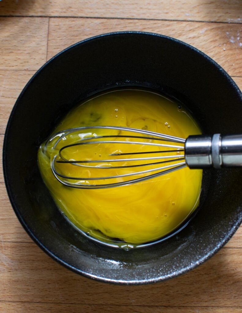 Egg yolks in a small in a small mixing bowl beaten with a whisk.