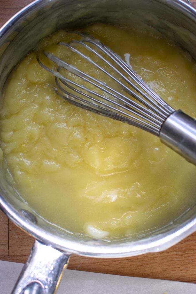 Butter, lemon juice and lemon zest added to sugar/egg yolk mixture and cooked on the stove top to further thicken.