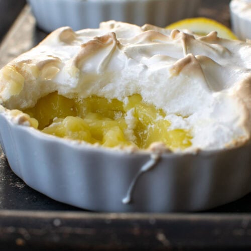 A crustless lemon meringue tart with a spoonful removed to show the lemony inside.