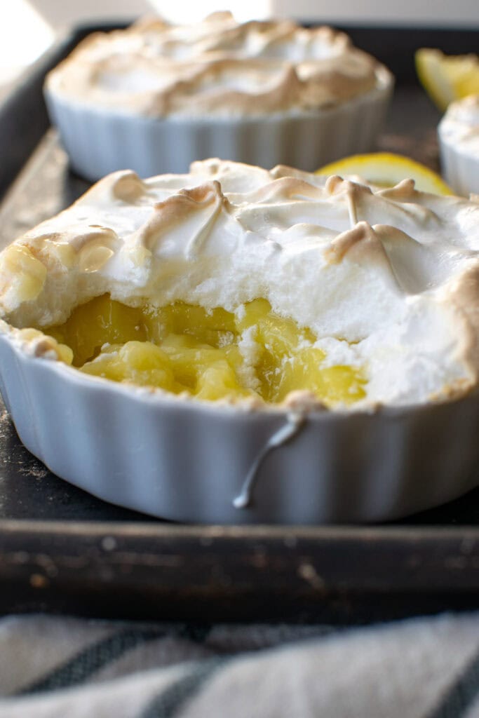 A crustless lemon meringue tart with a spoonful removed to show the lemony inside.