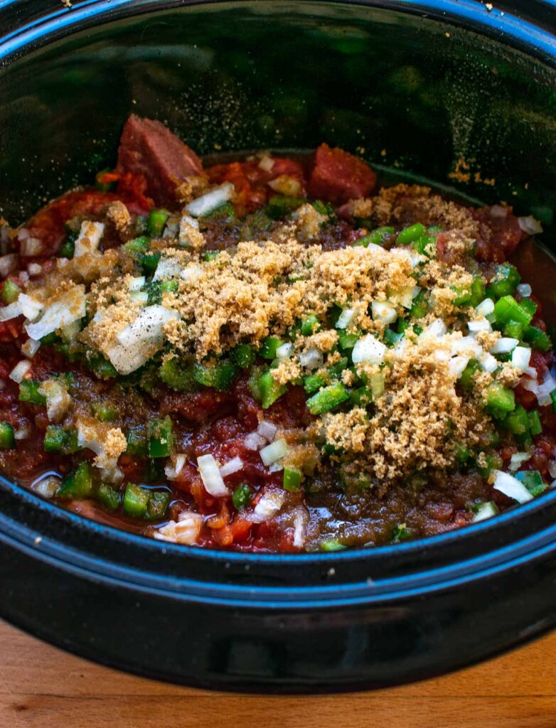 Green peppers, chopped onions, brown sugar and spices added to a slow cooker with cubed stewing beef.