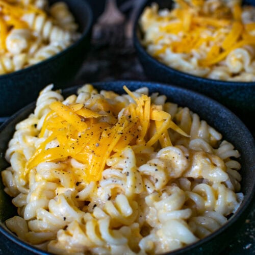 3 bowls of macaroni and cheese made with spiral noodles and sprinkled with shredded cheddar.