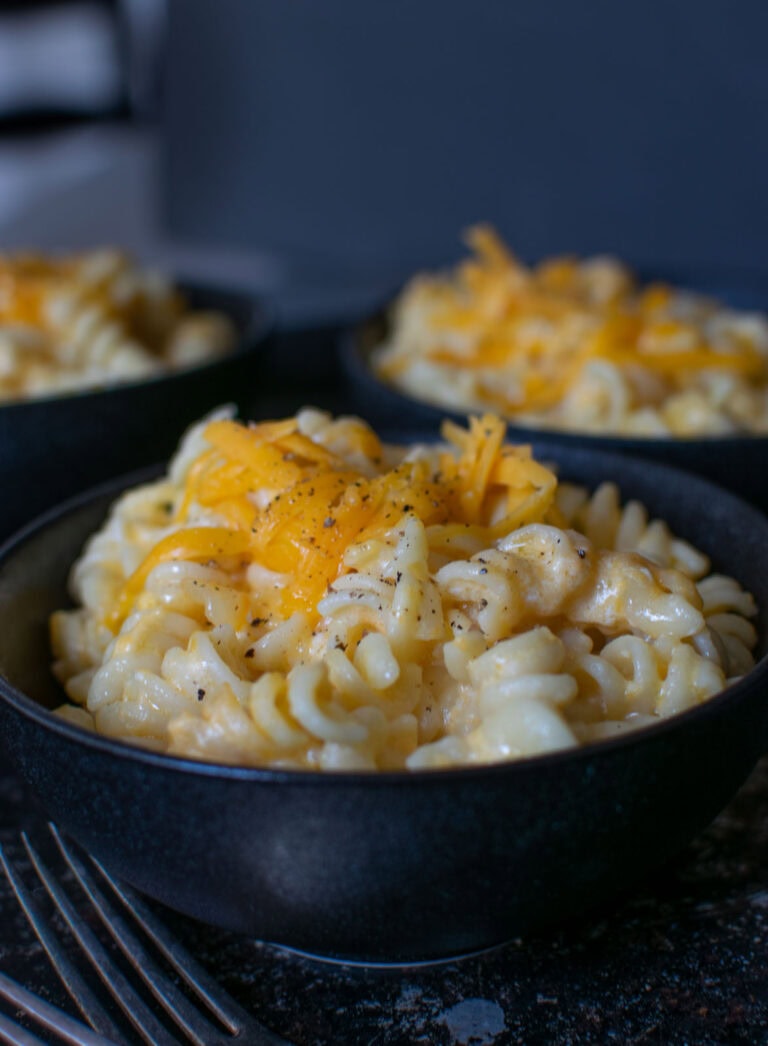 A black bowl filled with spiral macaroni and cheese.