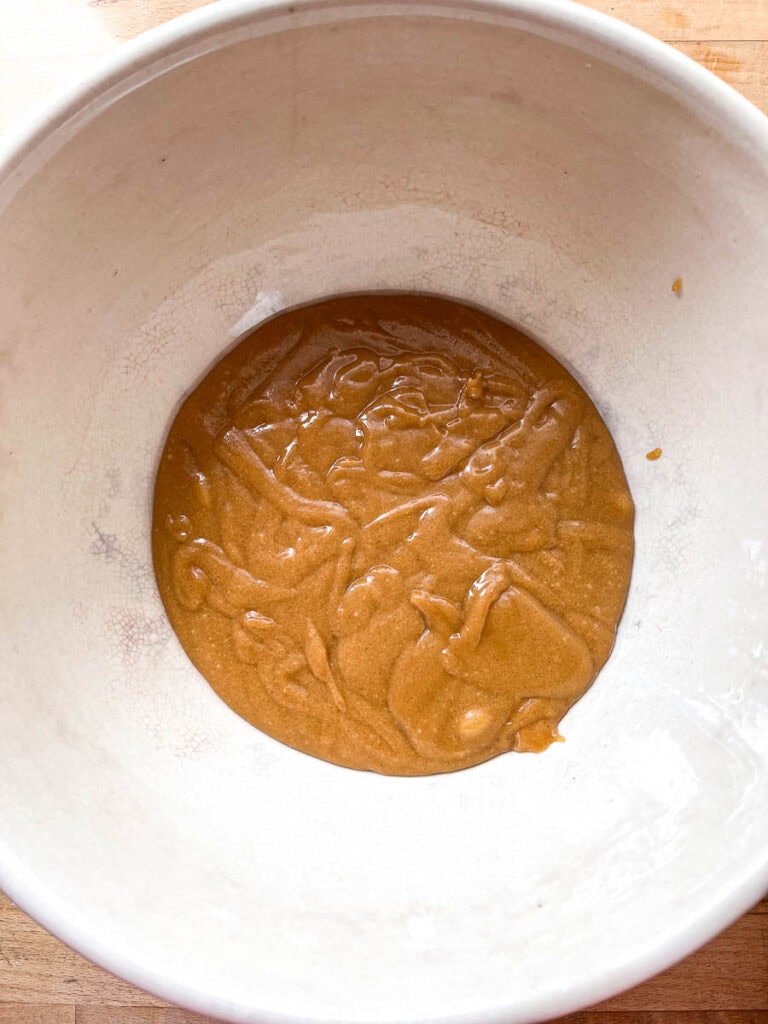 The base for sweet Marie crispy bars made of melted peanut butter, brown sugar and corn syrup in a large mixing bowl.