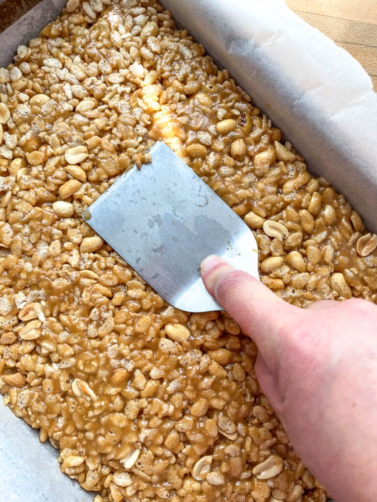 The chewy crispy peanut butter base for sweet Marie bars pressed into a 9 by 13 inch pan.