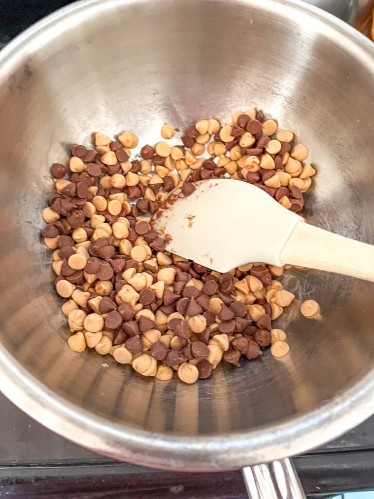 Chocolate and butterscotch chips in a bowl over a pot of simmering water.