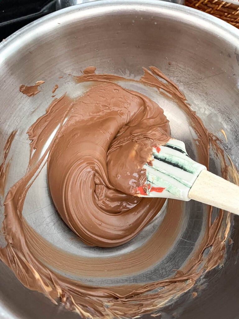 Melted chocolate and butterscotch chips in a bowl over a pot of simmering water on the stove top.