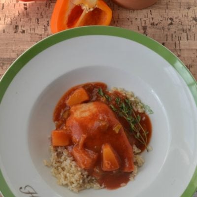 A bowl of sweet and sour chicken served over rice.