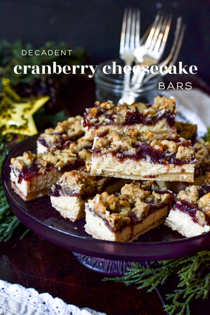 A plate of cheesecake bars topped with cranberries and walnut crumble.