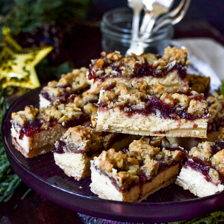 Slices of cheesecake bars topped with cranberries and a walnut crumble topping.
