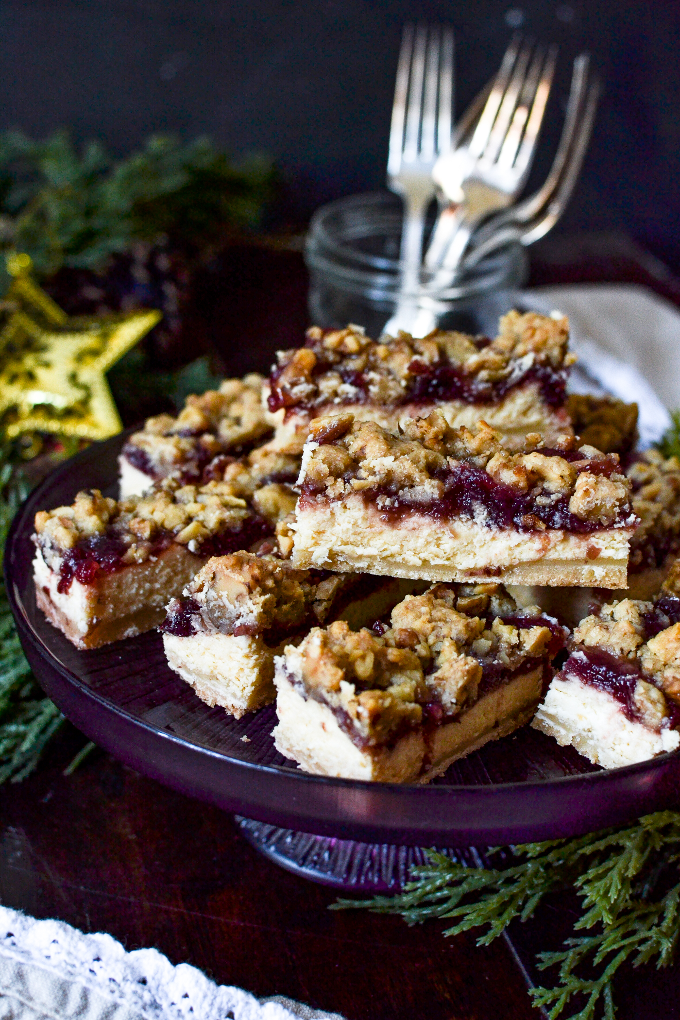 Slices of cheesecake bars topped with cranberries and a walnut crumble topping.