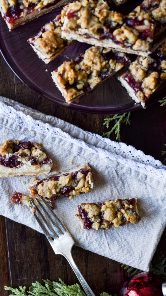 overhead view of cranberry cheesecake bars on a beige napkin with lace edges.