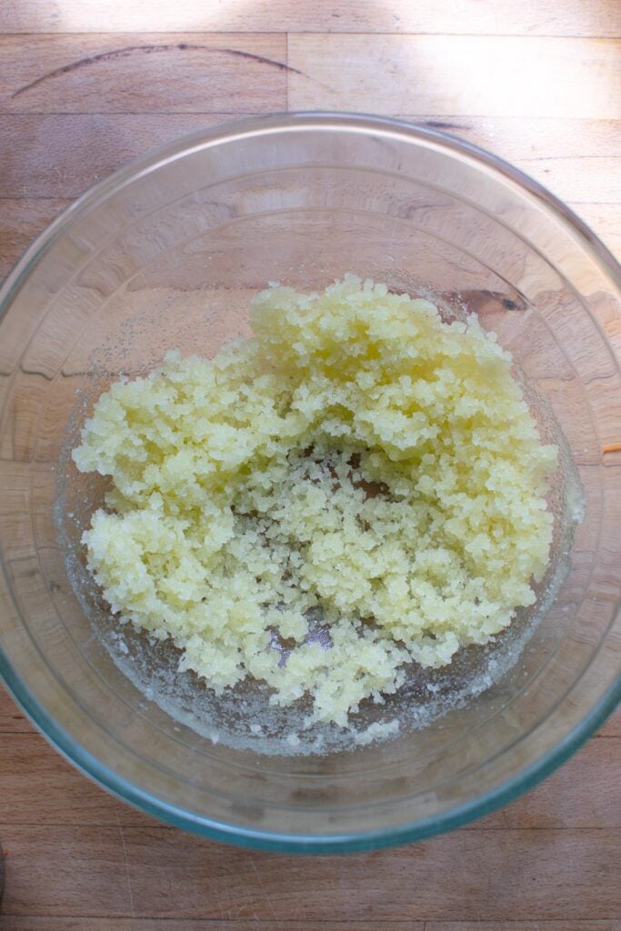 Olive oil and granulated sugar mixed together in a glass mixing bowl.