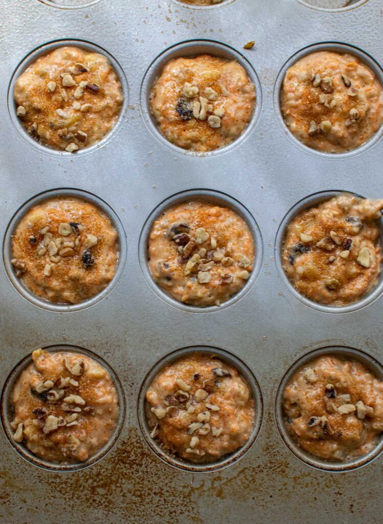 Morning glory muffin batter divided between 9 muffin tins before baking.