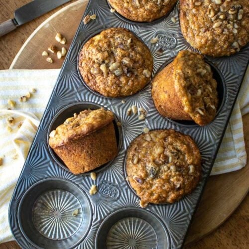 A muffin tray filled with freshly baked muffins, some turned on their side to show the muffin top.
