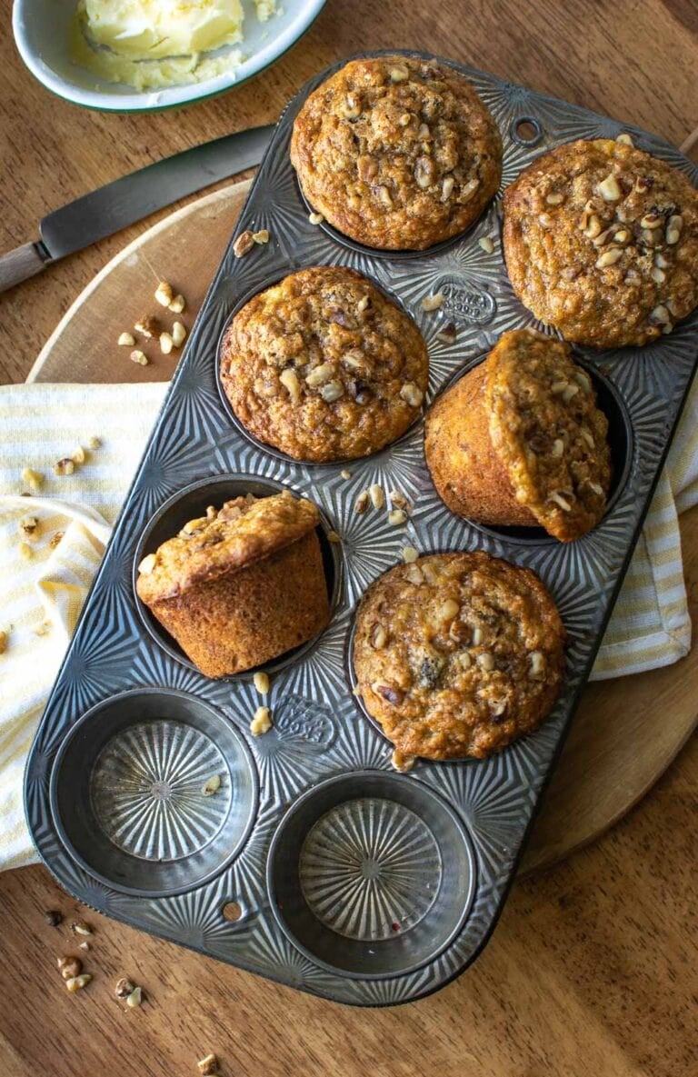 A muffin tray filled with freshly baked muffins, some turned on their side to show the muffin top.