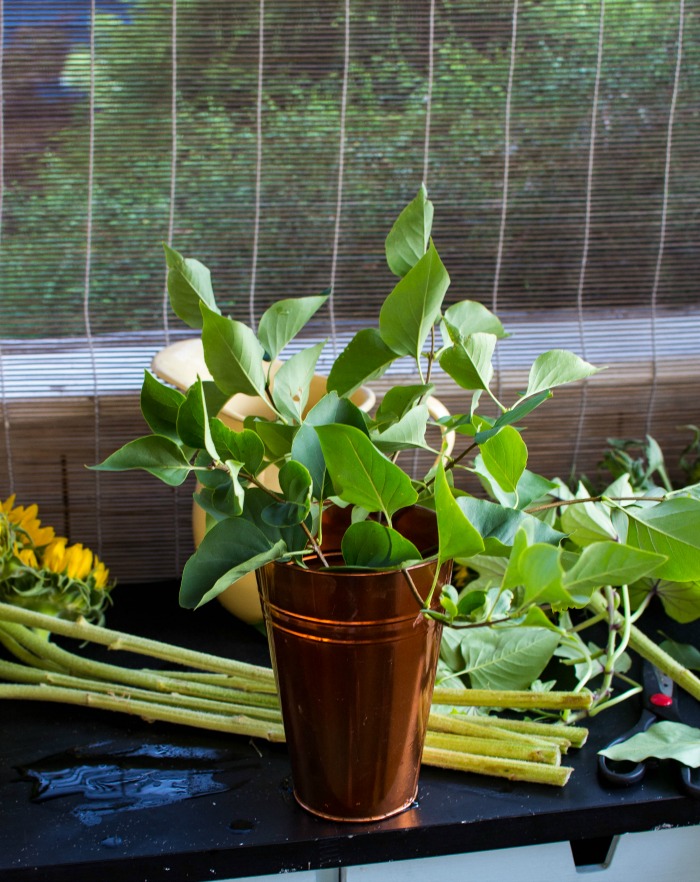Creating a base of greens for sunflower arrangements