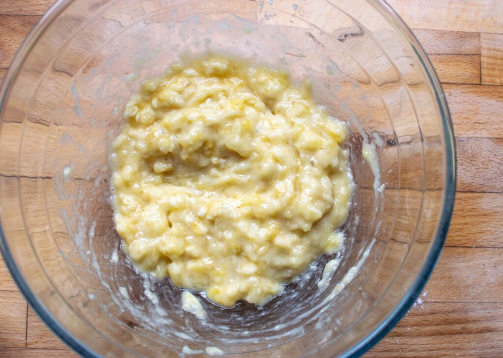 Mashed bananas in a glass mixing bowl.