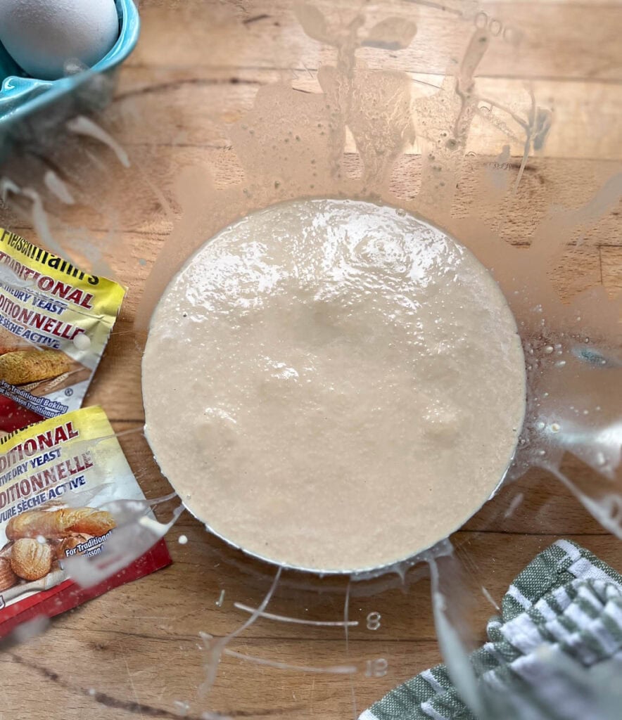 Active yeast proofing in a large mixing bowl to make cinnamon roll dough.