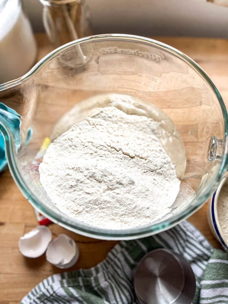 Flour added to proofed active yeast in a large stand mixer mixing bowl.