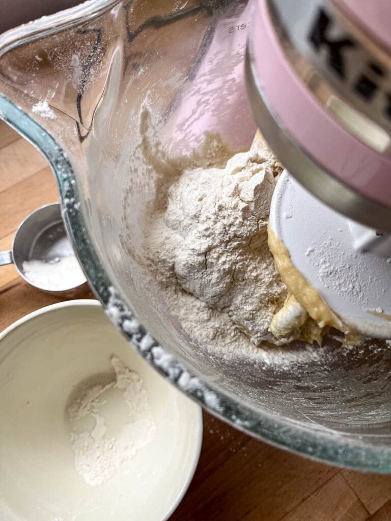 Cinnamon roll dough being mixed and kneaded in a bowl on a stand mixer.