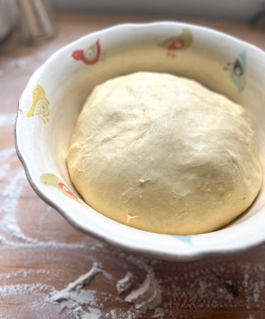 Cinnamon roll dough that has doubled in size in a large bowl after proofing.