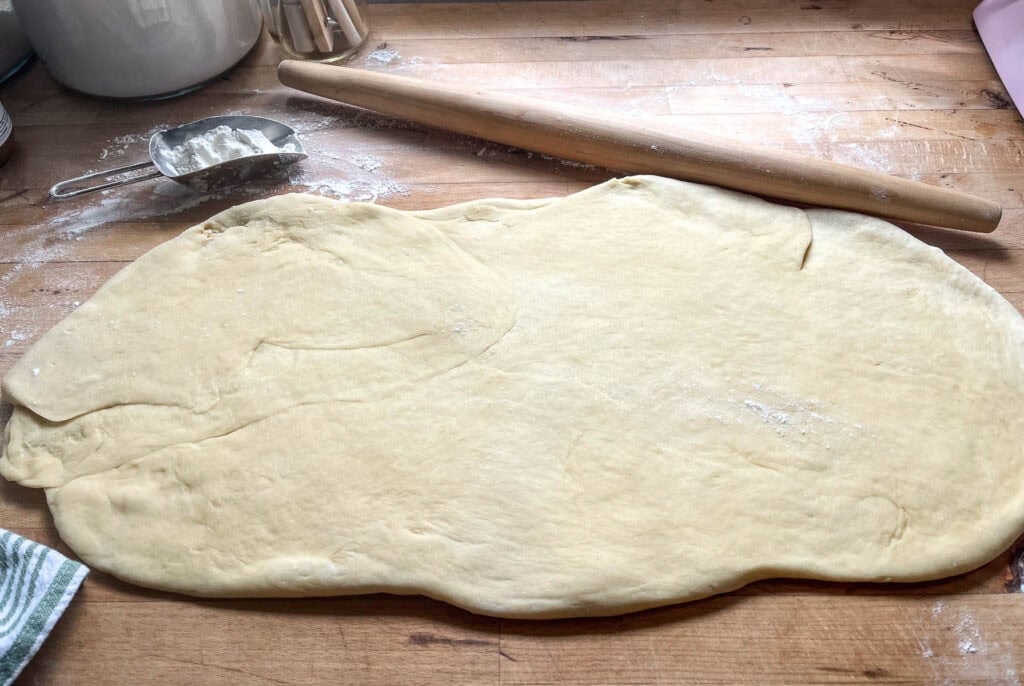 Cinnamon roll dough rolled out into a long rectangle.