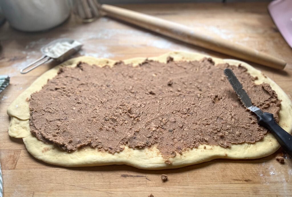 Brown sugar, butter and chopped pecan filling spread out over cinnamon roll dough.